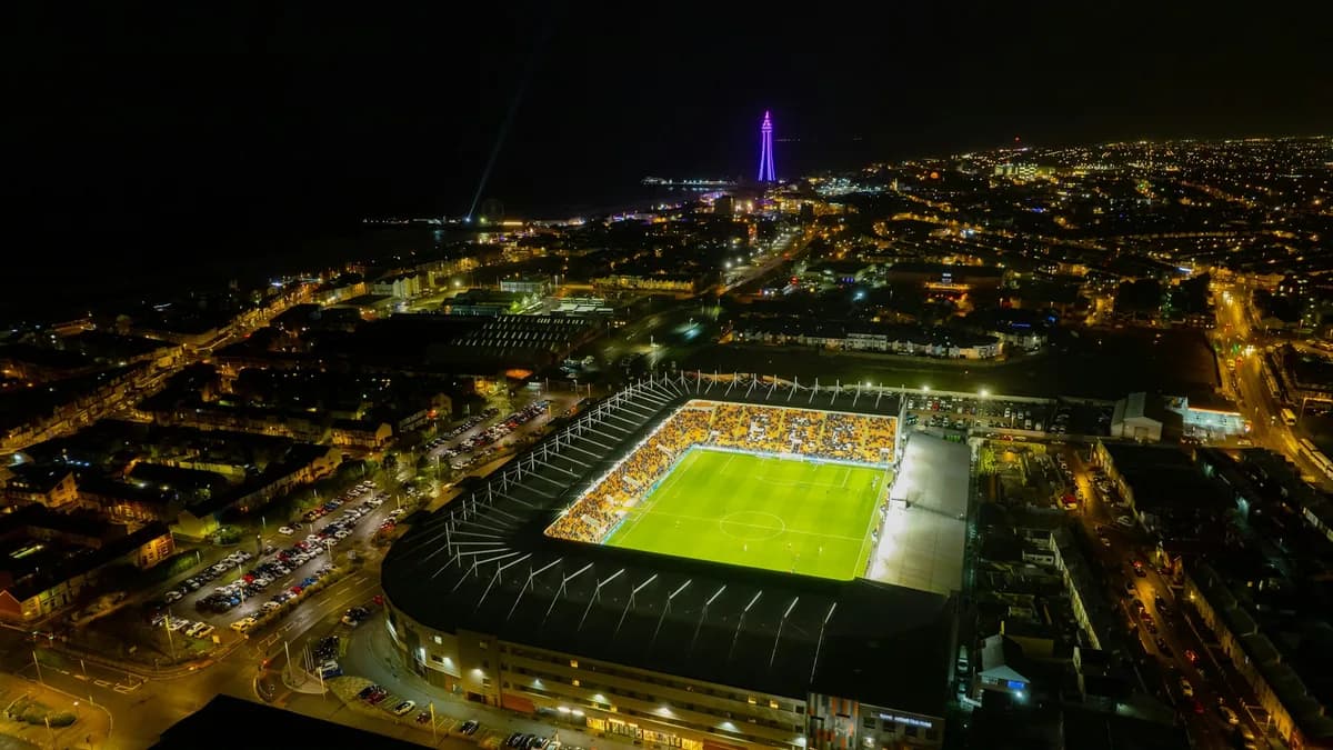 Luftaufnahme eines beleuchteten Fußballstadions bei Nacht inmitten der Stadt