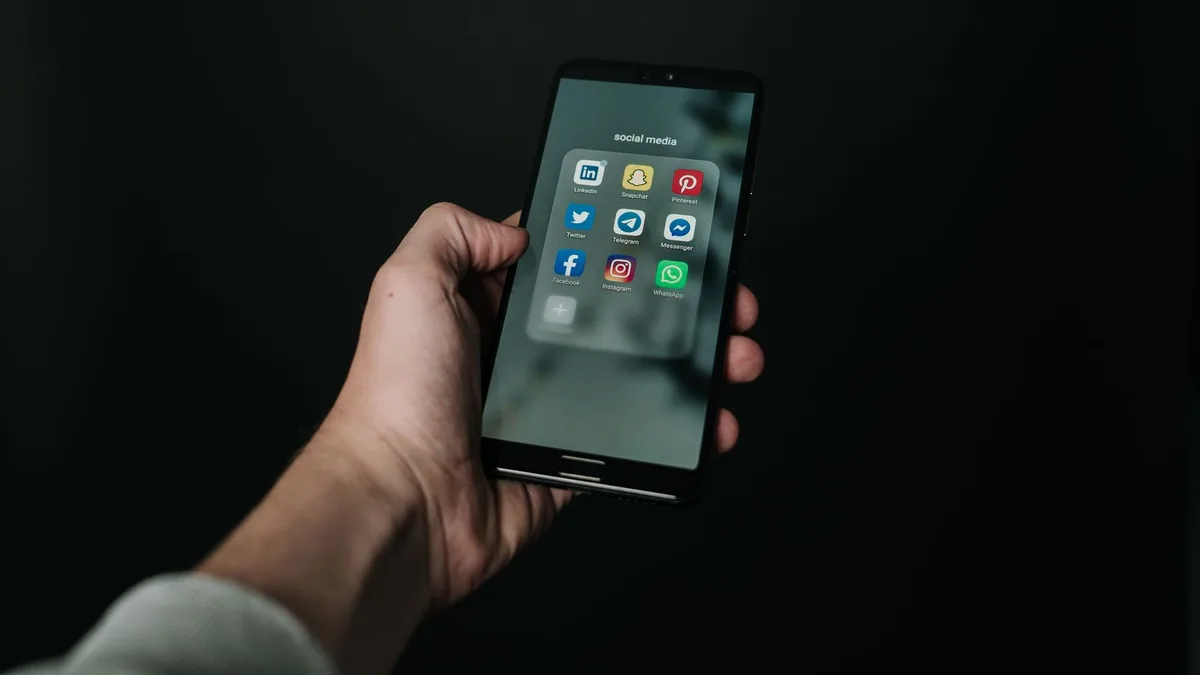 Hand hält ein Android-Smartphone mit dunklem App-Bildschirm