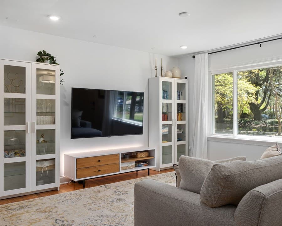 Helles Wohnzimmer mit großem, wandmontiertem Fernseher und Sideboard